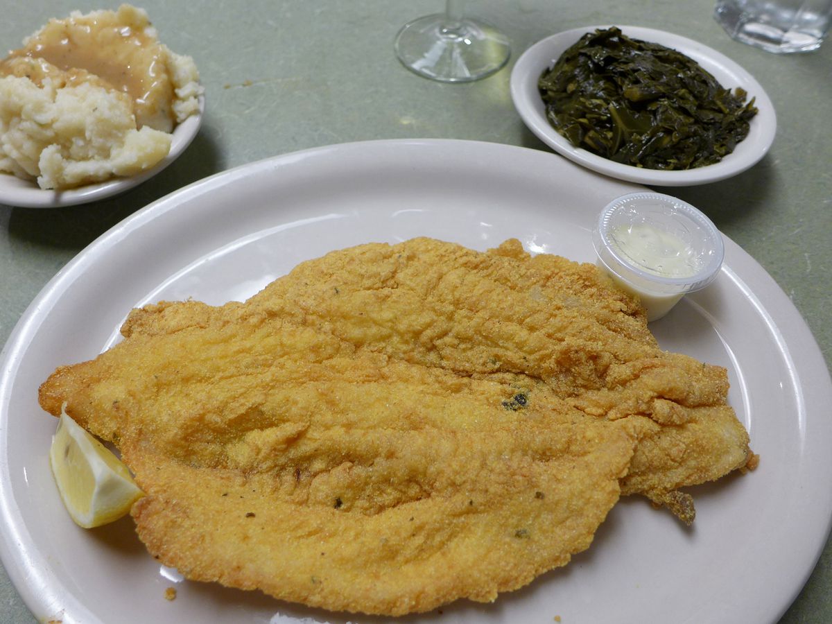 A large fish filet with breading accompanied by two side dishes.