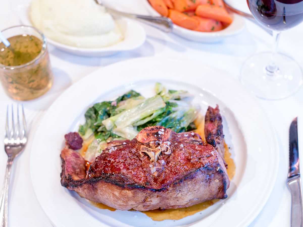 A tantalizing mutton chop served on a pristine white plate, accompanied by a knife and fork on a beautifully set table.