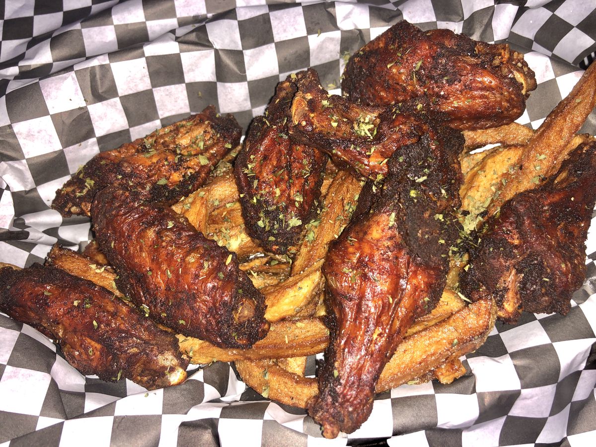 Wings with fries in a checkered wrapped basket.
