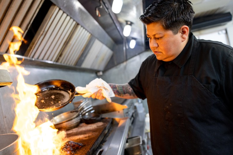 Chef Kirk grills chicken marinated in tamarindo for a pollo asado dish in the kitchen of Ocho at Hotel Havana.