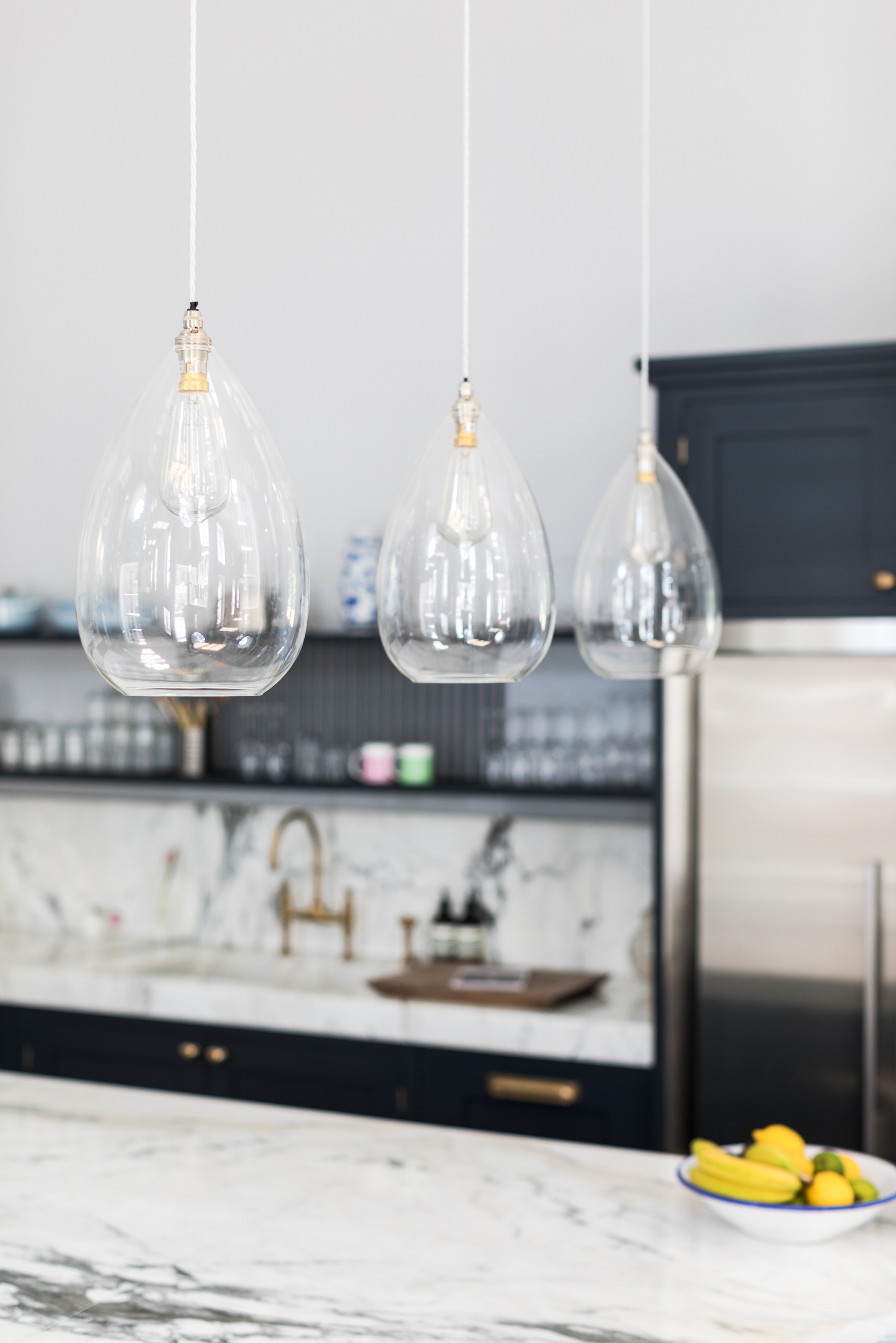 Three glass pendant shades above island in kitchen