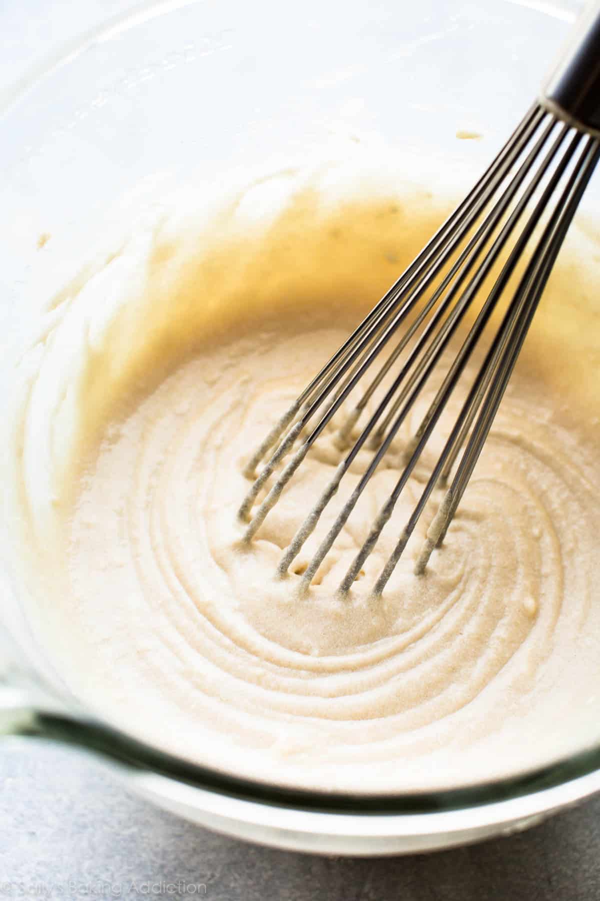 vanilla cake batter in a glass bowl with a metal whisk