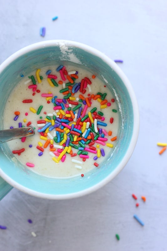 vanilla cake batter un a mug with rainbow sprinkles